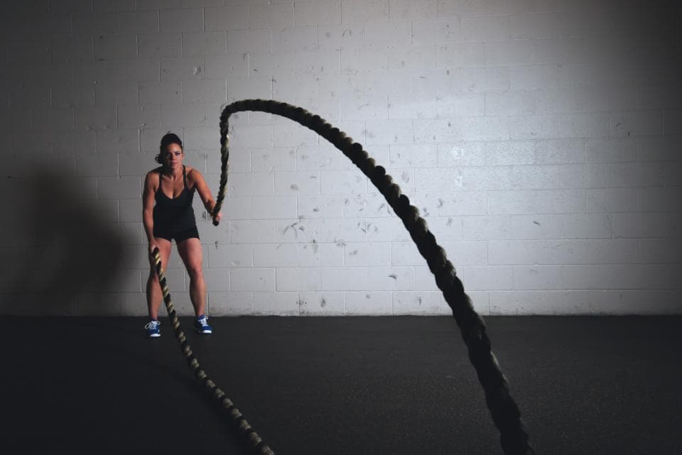 A woman training with battle ropes in a dark gym