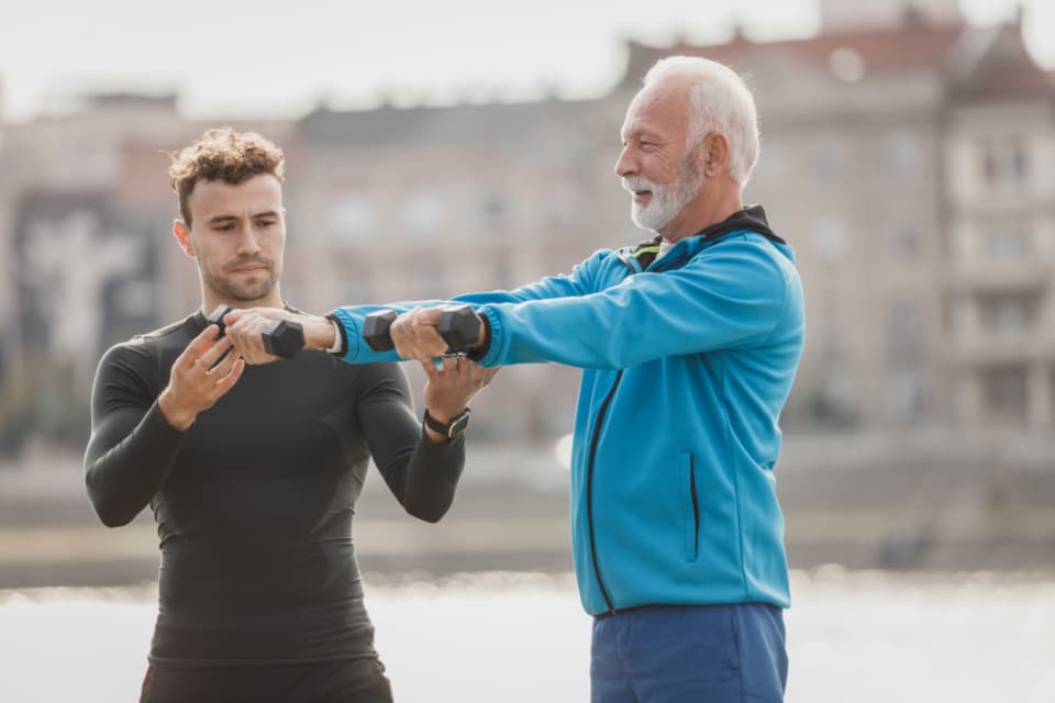 A coach guiding a member through a dumbbell exercise